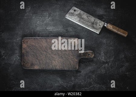 Rustic Cutting Board and Meat Cleaver on Dark Background. Butcher Shop Tool. Stock Photo