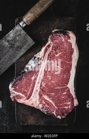 Premium Dry Aged Raw T-bone Steak on Rustic Kitchen Chopping Board. USDA Prime Beef. Stock Photo