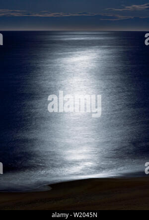 Moonlight reflects on the waves crashing along the shore at twilight n Virginia Beach, Virginia. Stock Photo