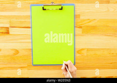 Office Hand Holding a Folder with a Green Color Paper on the Background of the Wooden Table. Copyspace. Place for Text Stock Photo