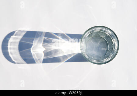 Glass beaker from which padajet sharp shadow, stands on a white background. Empty space for text Stock Photo