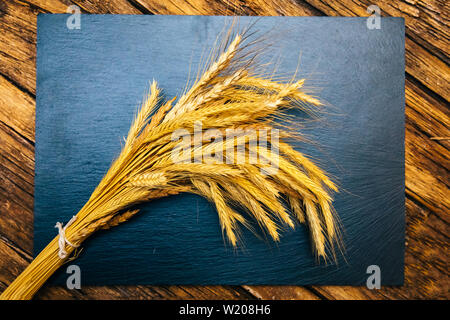 Ear of wheat or spike on the black background wooden table. Bakery or bread concept image. Stock Photo
