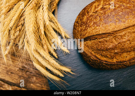 Assortment of baked fresh various rye, loaf or whole grain brown bread, wheat ear or spike and flour on wooden board table. Bakery concept image.