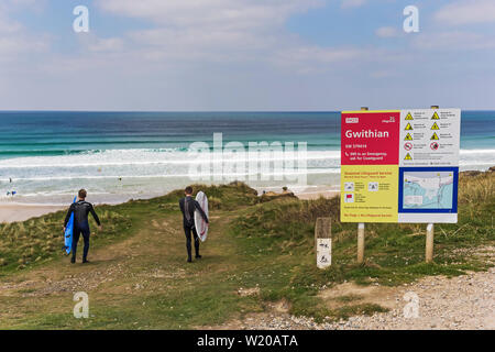 Surfers head for the beach at Gwithian, Cornwall, UK Stock Photo