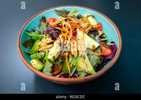 Healthy vegetables green caesar or greek mediterranean salad with boiled egg and fruits in white porcelain dish on table for vegetarian on black backg Stock Photo