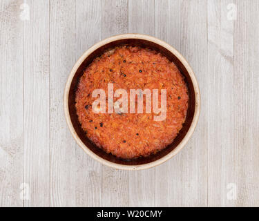 A ceramic pot of traditional Eastern European stewed cabbage on a white wooden kitchen board. Stock Photo