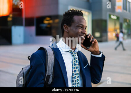African American businessman holding mobile phone wearing blue suit Stock Photo