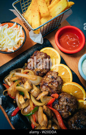 Grilled or roasted minced meat or meatballs food meal and vegetables with french fries potatoes in cafe or restaurant. Dinner or lunch table concept Stock Photo