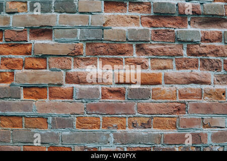 Urban wall from a red brick with a regular laying with scratched surface and grange stains. Stock Photo