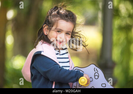 Cute girl enjoying on playground in the park in summertime . Stock Photo