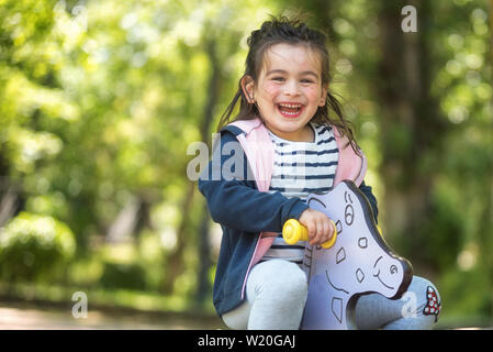 Cute girl enjoying on playground in the park in summertime . Stock Photo