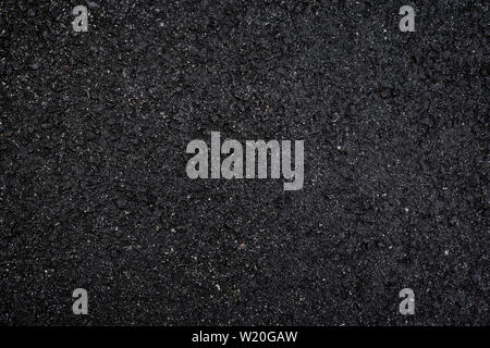 Close-up of wet, black asphalt, viewed from above. High resolution dark full frame textured background. Stock Photo