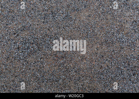 High resolution full frame textured background of wet sandy ground with gravel, viewed from above. Stock Photo