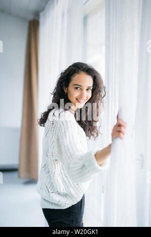 people and hope concept - close up of happy woman opening window curtains Stock Photo