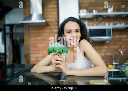 Strong woman with broccoli in the kitchen. Stock Photo