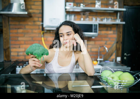 Strong woman with broccoli in the kitchen. Stock Photo