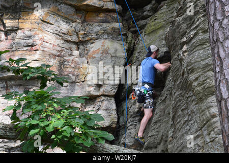 A young male climber works his way up a cliff face on the Ledge Spring Trail at Pilot Mountain State Park in North Carolina. Stock Photo