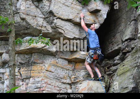 A young male climber works his way up a cliff face on the Ledge Spring Trail at Pilot Mountain State Park in North Carolina. Stock Photo