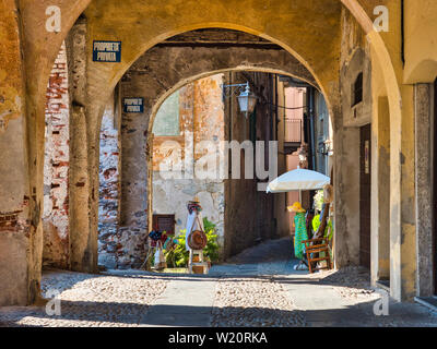 Orta San Giulio Arch alley in Lake Orta Italy with clothes at display without people during a summer afternoon Stock Photo