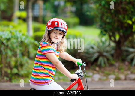 Kids on bike in park. Children going to school wearing safe bicycle helmets. Little girl biking on sunny summer day. Active healthy outdoor sport for Stock Photo