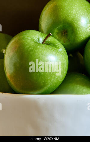 Green Granny Smith cooking apples in a white bowl. Stock Photo