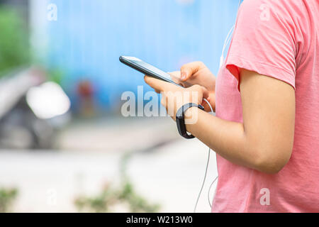 Hand of a woman wearing a watch and holding the phone plugged in headphones. Stock Photo