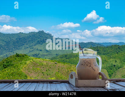Isolated Iced coffee in a glass jar on Bamboo flooring Background mountains with clipping path. Stock Photo
