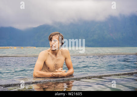 Geothermal spa. Man relaxing in hot spring pool. Young man enjoying bathing relaxed in a blue water lagoon, tourist attraction Stock Photo