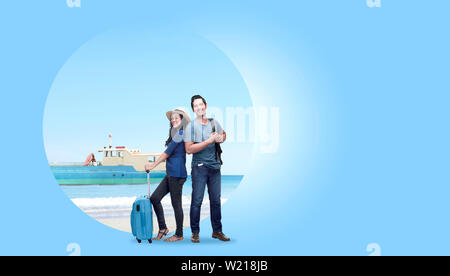 Asian couple with suitcase bag and backpack standing with sandy beach background and ferry boat sailing on the sea. Traveling concept Stock Photo