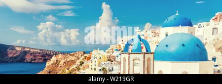 Three Domes church panoramic view of Santorini island, Oia village, Greece. Famous Europe travel european destination greek island. Horizon landscape banner crop for advertisement copyspace. Stock Photo