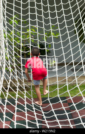 Boy climbing a rope net on the playground. Stock Photo