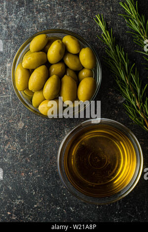 Green olives and olive oil in glass bowl. Flat view. Stock Photo