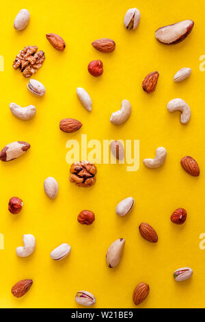 A variety of nuts are scattered on a yellow background. Flat lay. View from above. Copy space Stock Photo