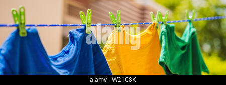 Multicolor shirts on clothesline in sunny day BANNER, LONG FORMAT Stock Photo