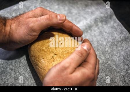 man's hands knead the dough in retro style on a dark background. Stock Photo