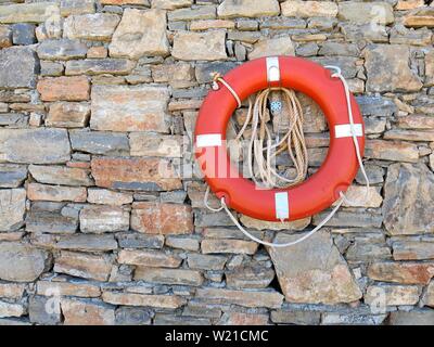 Life ring with line attached to it hanging on a wall at a holiday resort. Stock Photo