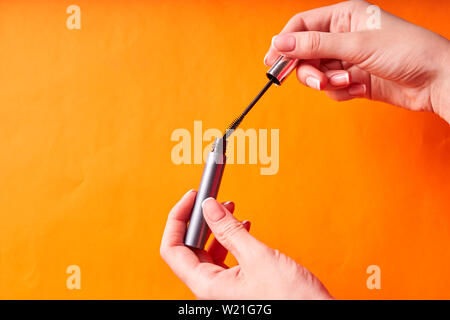 eye mascara in women's hands on orange background. Stock Photo