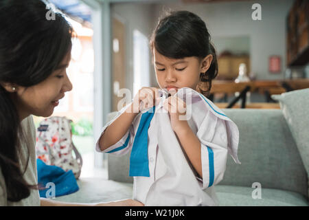 mother help her toddler kid preparing for school in the morning. young kindergarten student wearing school uniform Stock Photo