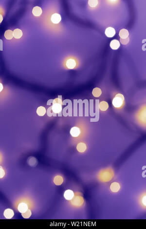 Golden festive bokeh lights on blurred violet background. Christmas or party concept. Stock Photo