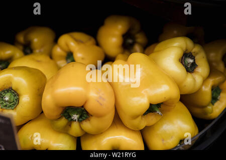 A close-up shot of an abundance of fresh Yellow peppers on display at a market stall. Stock Photo