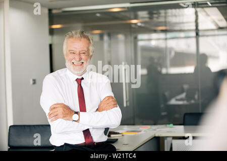 Happy handsome old businessman standing and smiling in office Stock Photo