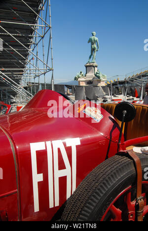 A vintage red car parked beside a beautiful yellow house under a cloudy ...