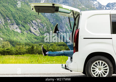 man sitting in car trunk looking at lake. beautiful landscape view. road trip concept Stock Photo