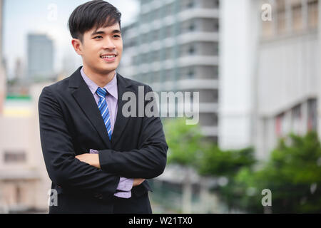 Happy handsome businessman standing and smiling  at outdoor Stock Photo