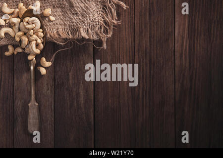 Cashew nuts on an old spoon and composition from old wood and material. Top view and empty space on right side for your text Stock Photo