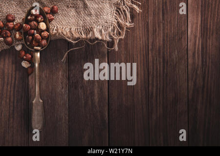 Hazelnuts on an old spoon and composition from old wood and material. Top view and empty space on right side for your text Stock Photo
