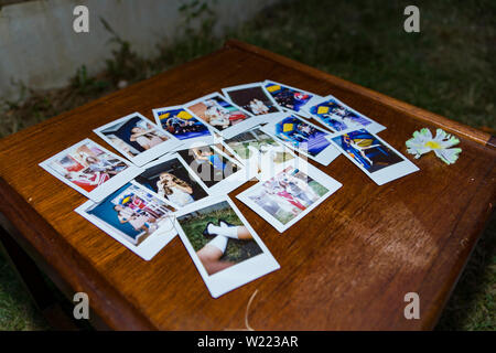 Collection of polaroid photo images taken from an instant camera, displayed on a wooden table Stock Photo