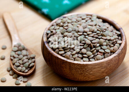 Green lentils in wooden bowl on wooden background. Stock Photo