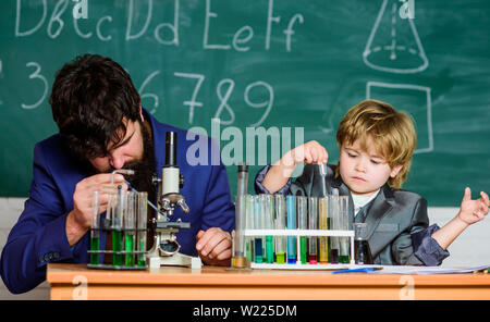 Touching Lives Forever. father and son at school. teacher man with little boy. school lab equipment. Back to school. using microscope in lab. student doing science experiments with microscope in lab. Stock Photo