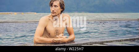 Geothermal spa. Man relaxing in hot spring pool. Young man enjoying bathing relaxed in a blue water lagoon, tourist attraction BANNER, LONG FORMAT Stock Photo